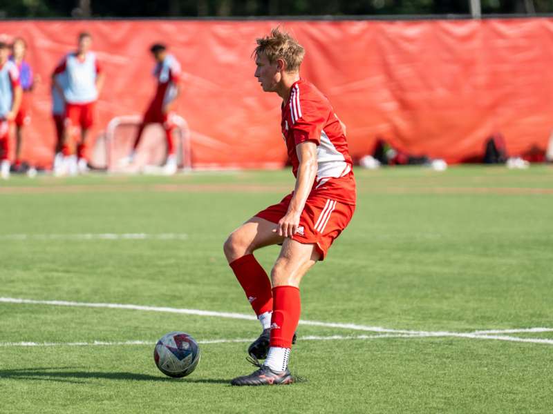 a man in a red uniform kicking a football ball