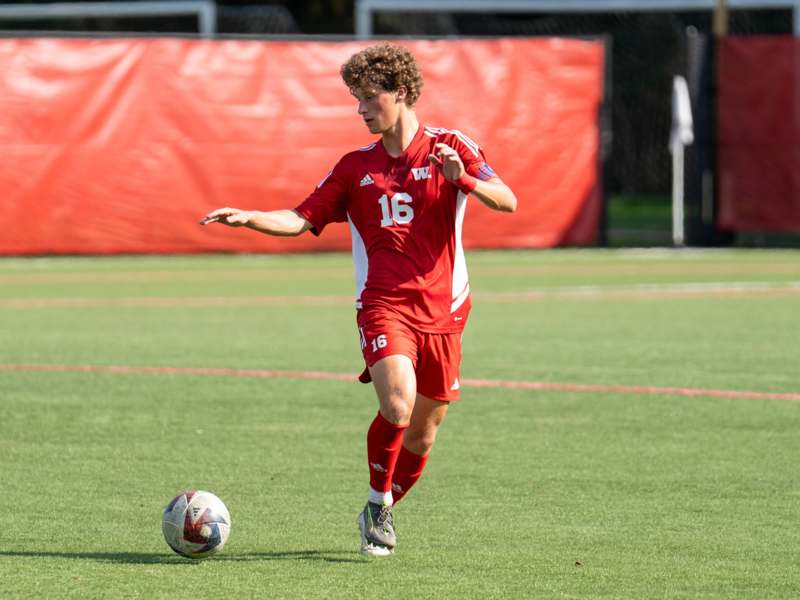 a man in a red uniform kicking a football ball