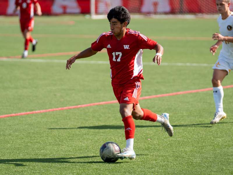 a man in a red uniform kicking a football ball