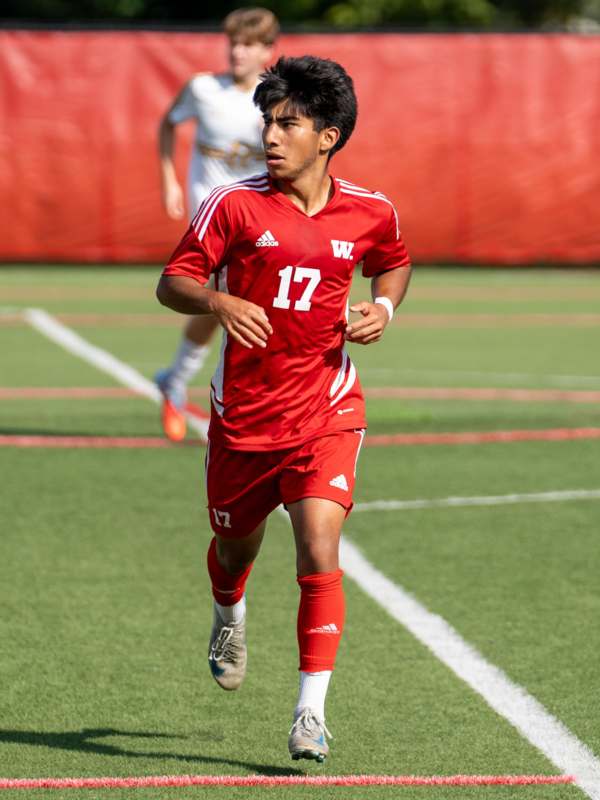 a man in a red uniform running on a field