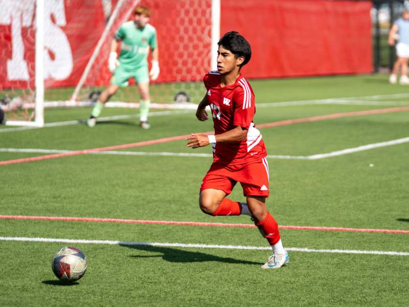 a man in a red uniform kicking a football ball