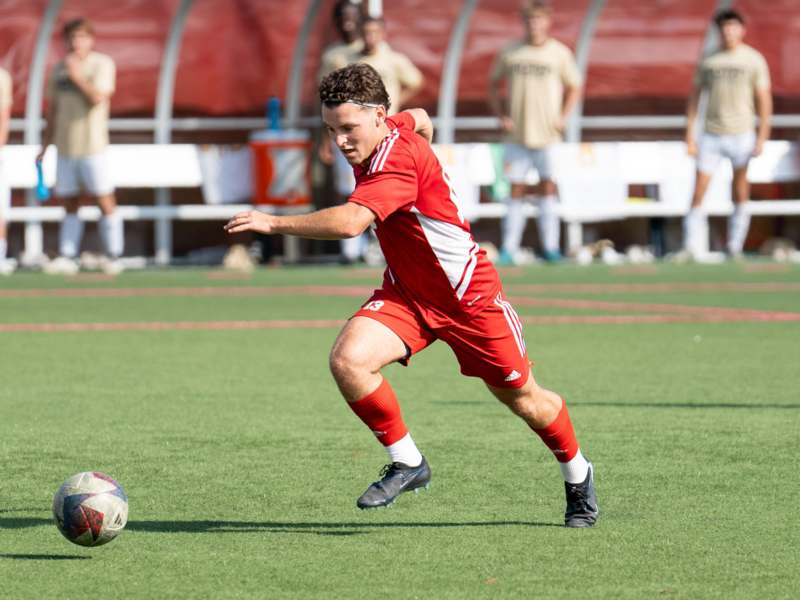 a man in a red uniform kicking a football ball