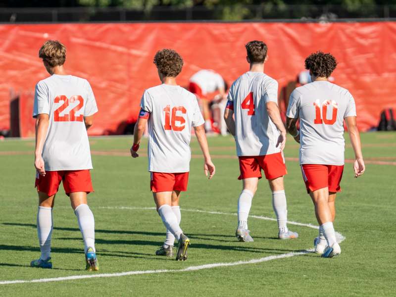 a group of men in white shirts and red shorts on a field