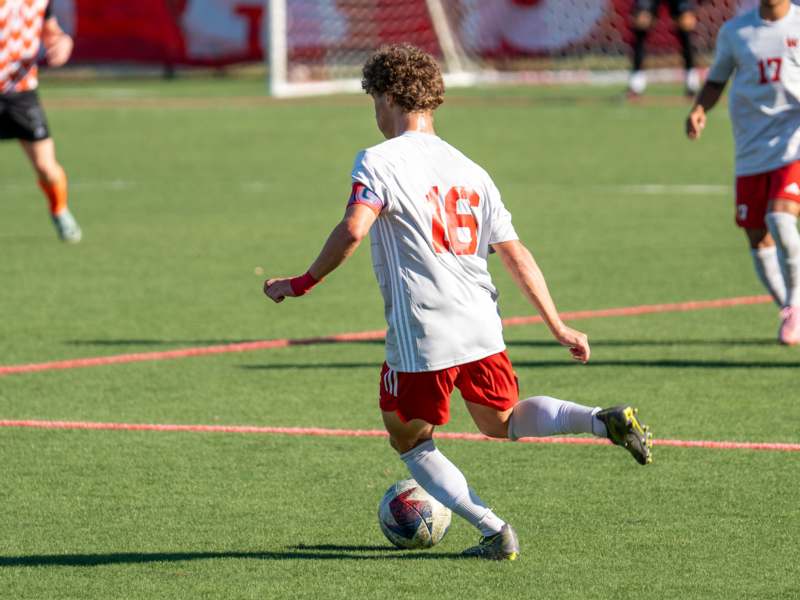 a man in a white jersey kicking a football ball