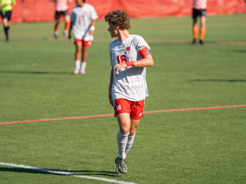 a man in a white jersey and red shorts running on a field