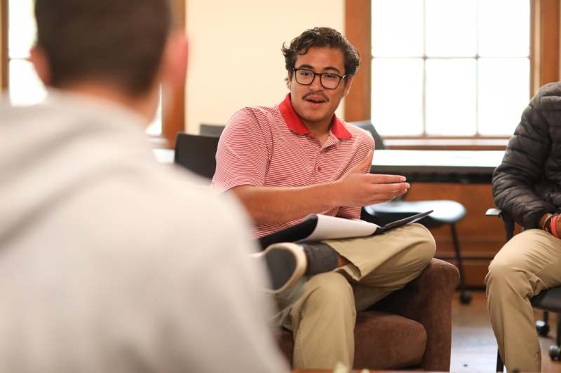 a man sitting in a chair with his legs crossed and a tablet in his lap