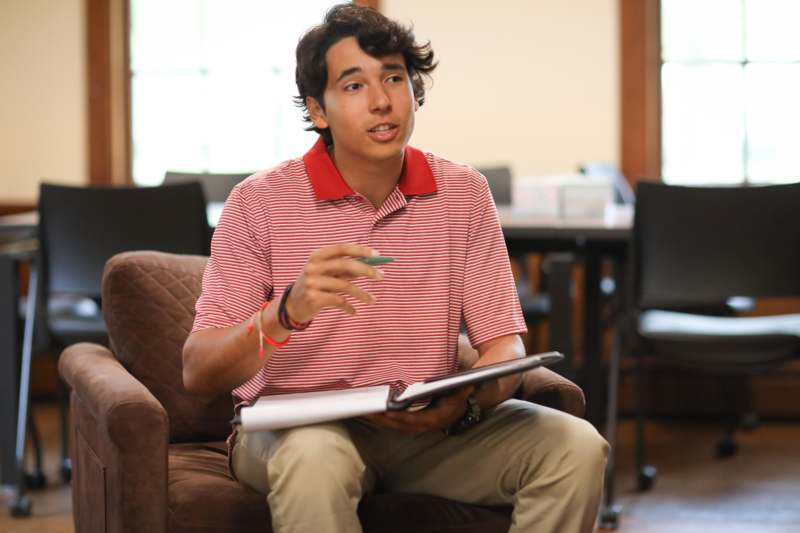 a man sitting in a chair holding a book and pen