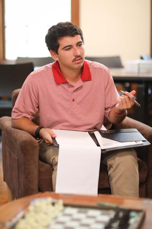 a man sitting in a chair holding a paper and a pen
