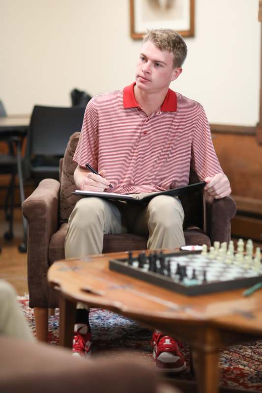 a man sitting in a chair holding a book and pen