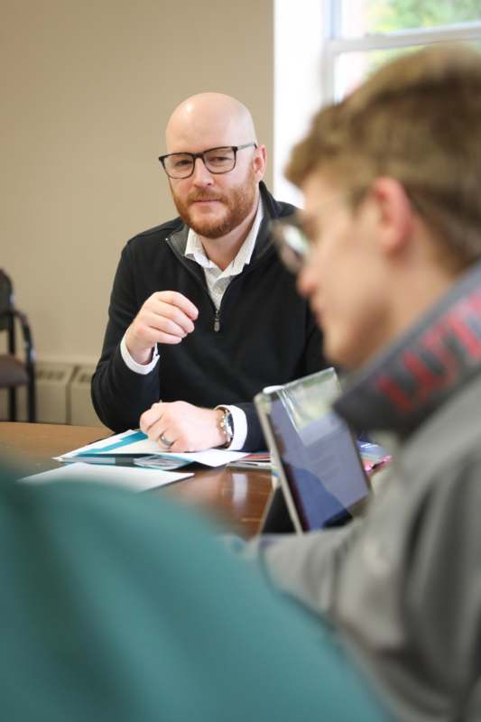 a man sitting at a table with a man in glasses