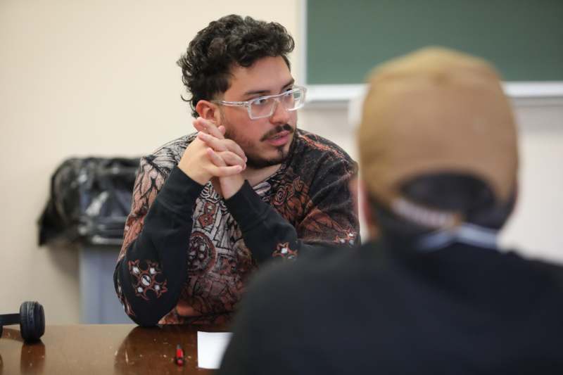 a man sitting at a table with his hands together