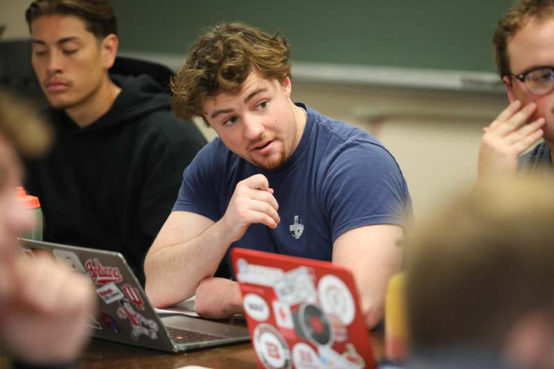 a man sitting at a table with laptops