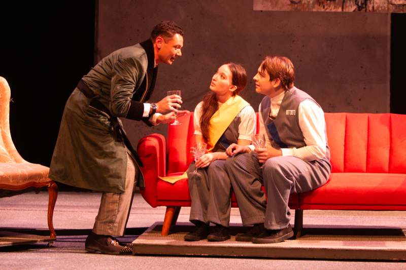 Wabash College Theater Presents 1984 - a man holding a glass of wine and a woman sitting on a red couch