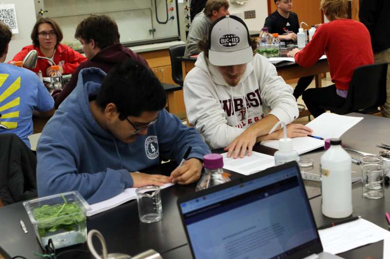 a group of people sitting at a table with laptops and papers