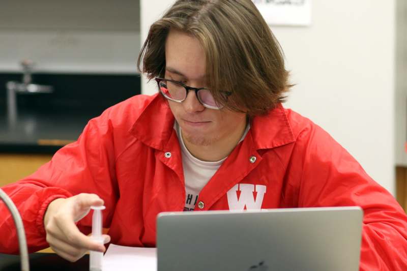 a man in glasses holding a small container