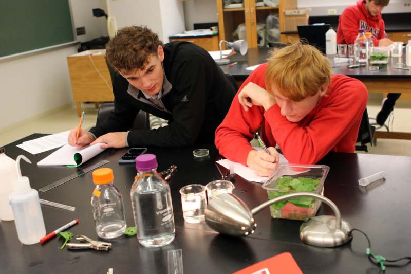 a group of people sitting at a table writing on paper
