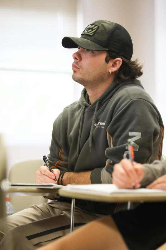 a man wearing a hat and holding pen and writing on a notebook