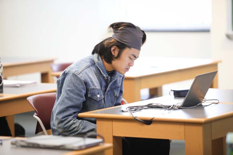a man sitting at a desk looking at a laptop