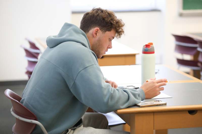 a man sitting at a desk looking at his phone