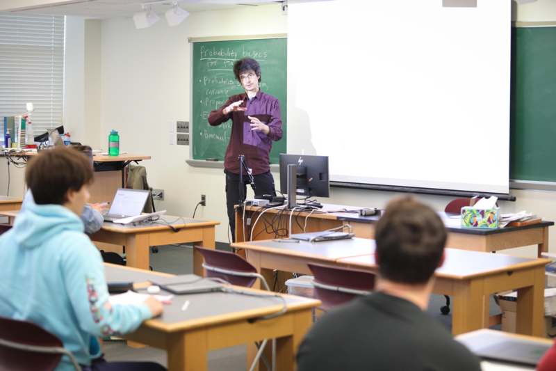 a man standing in front of a chalkboard in a classroom