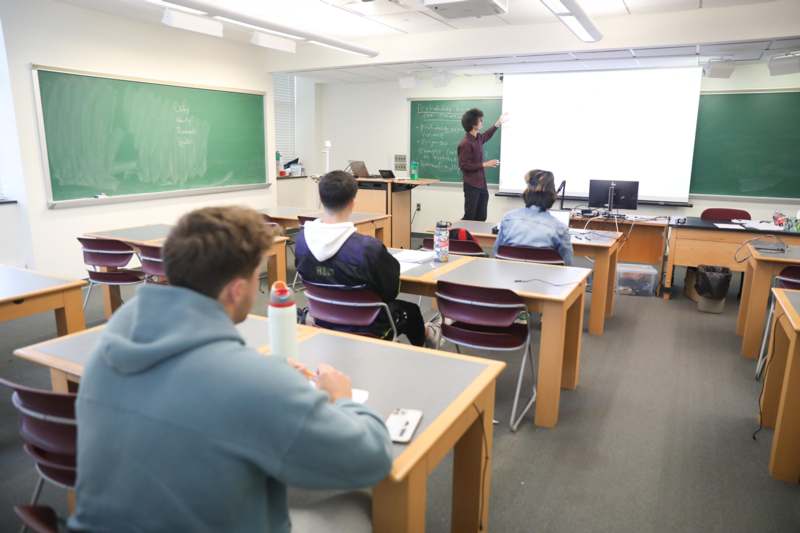 a woman standing in front of a whiteboard in a classroom