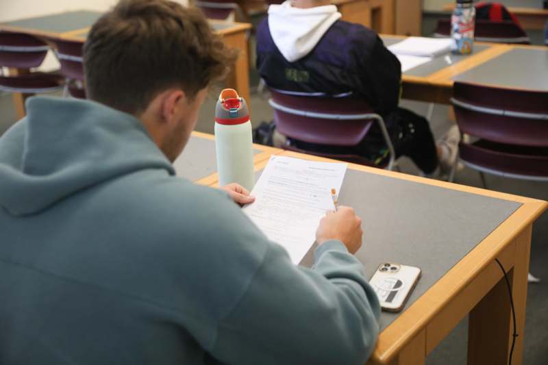 a man sitting at a desk writing on paper