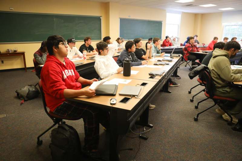 a group of people sitting at tables in a classroom