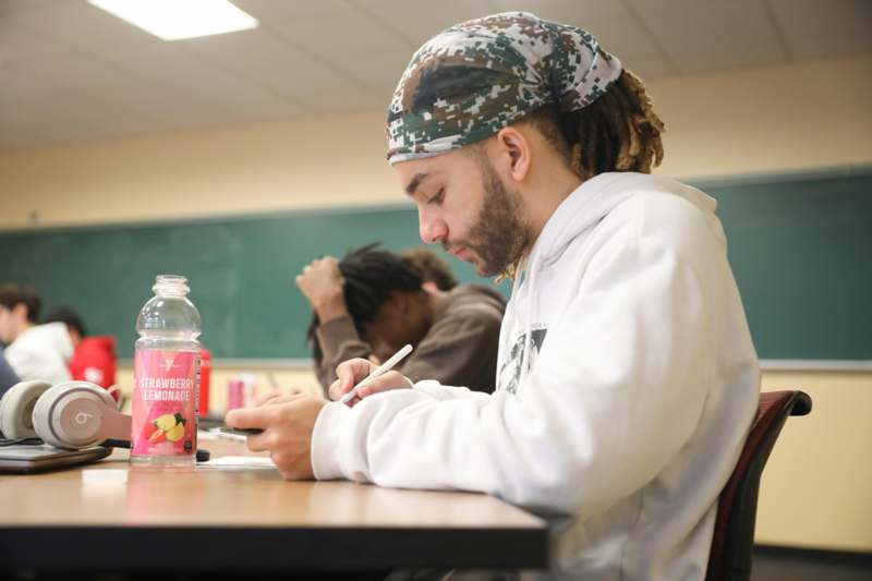 a man sitting at a desk writing on his phone