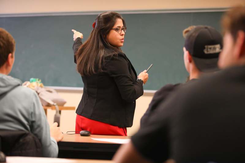 a woman pointing at a chalkboard