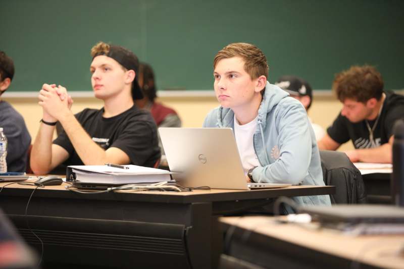 a group of people sitting at a desk with laptops