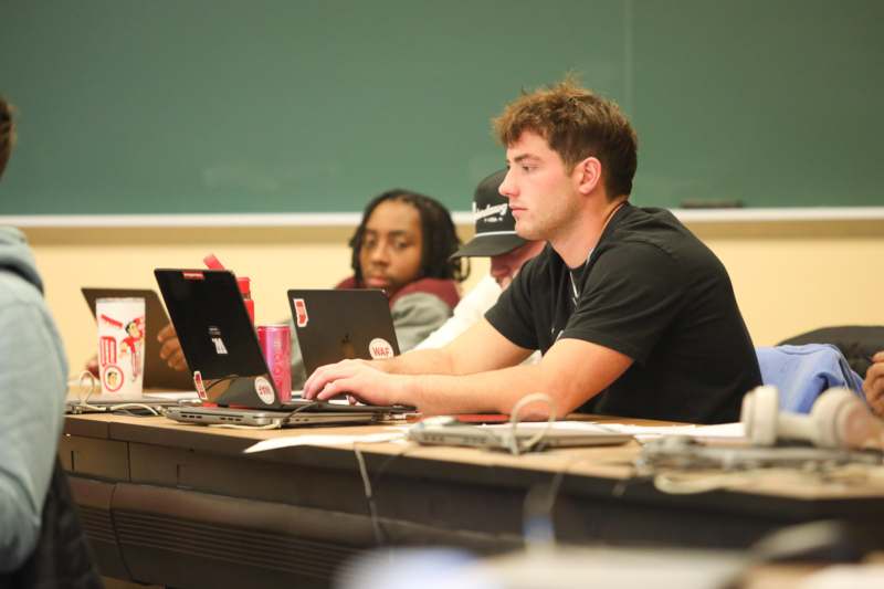 a group of people sitting at a table with laptops