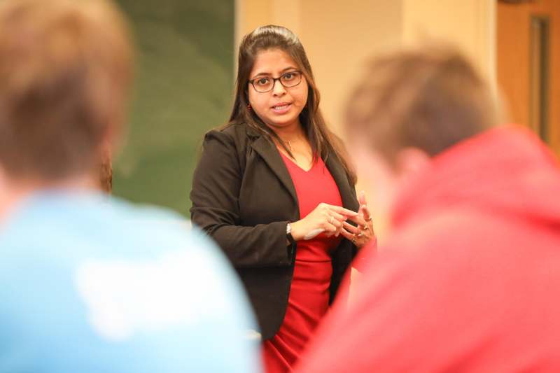 a woman in a red dress speaking to a group of people