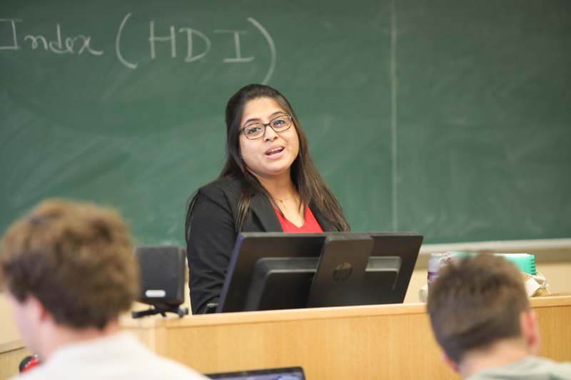 a woman standing in front of a green chalkboard