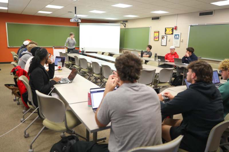 a group of people sitting at tables in a classroom