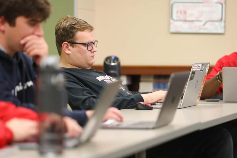 a group of people sitting at a table with laptops
