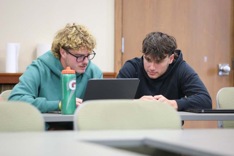 two men looking at a laptop