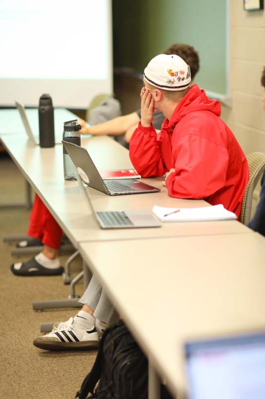 a group of people sitting at a table with laptops