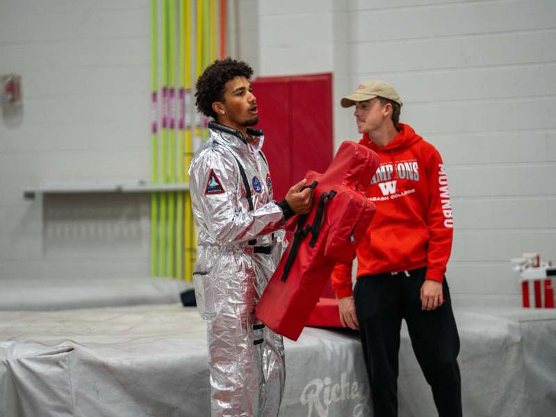 a man in a silver suit holding a red bag with a man in a red hoodie