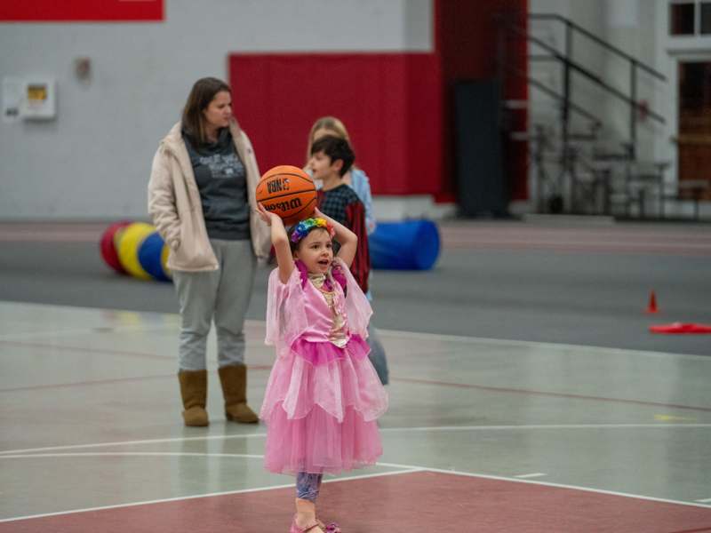 a girl in a pink dress holding a basketball
