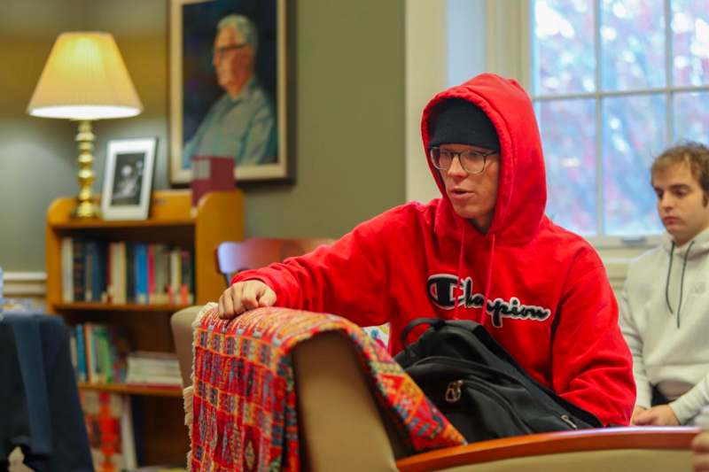 a man in a red hoodie sitting on a chair