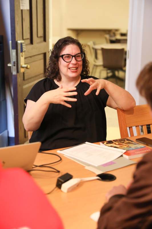 a woman sitting at a table with her hands in front of her