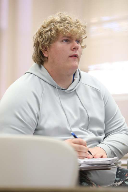 a man sitting in a chair with a pen and notebook