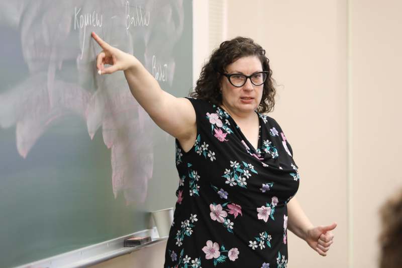 a woman pointing at a chalkboard