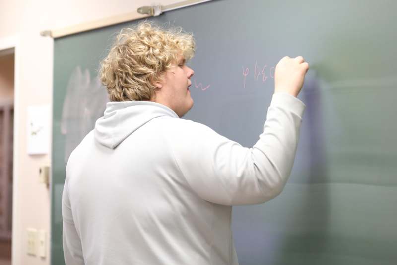 a man writing on a chalkboard
