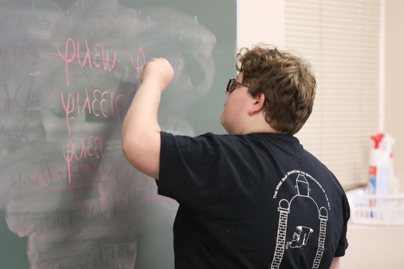 a man writing on a chalkboard