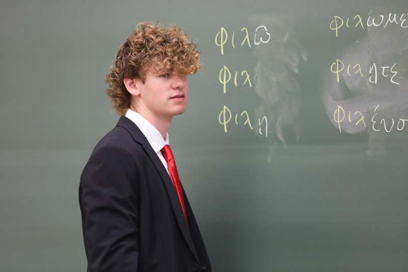 a man in a suit and tie standing in front of a chalkboard