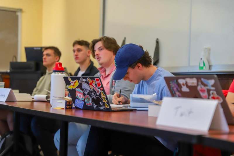 a group of people sitting at a table with laptops
