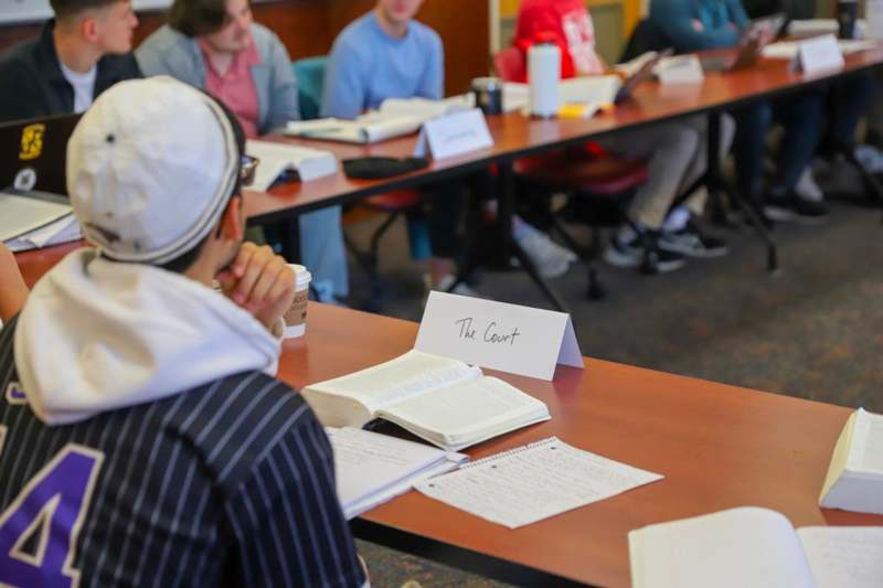 a group of people sitting at a table with books