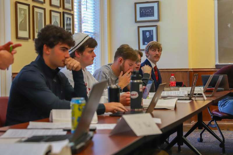 a group of people sitting at a table with laptops