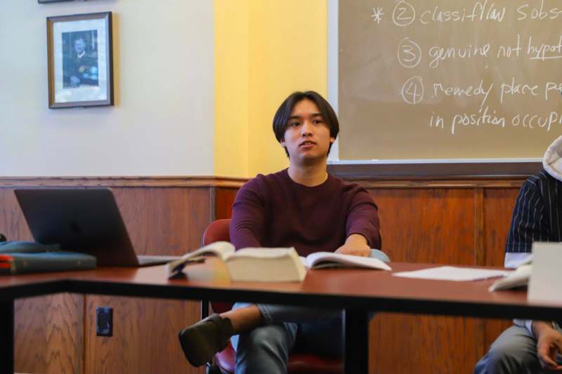 a man sitting at a desk with a laptop and a book